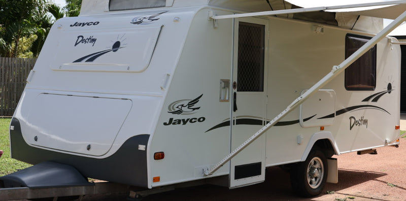 White Jayco travel trailer with an extended awning on a driveway.