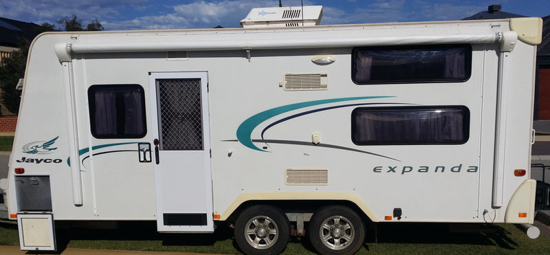 White Jayco Expanda travel trailer parked outdoors with a blue sky background.