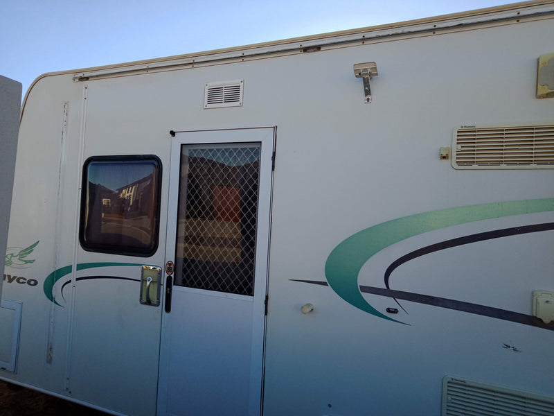 Side view of a white RV with a logo on a clear sky background