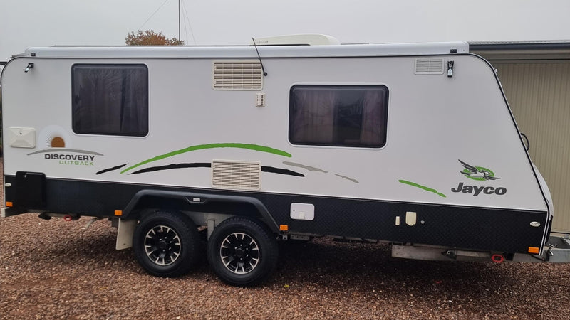 Jayco travel trailer parked on a gravel surface with a plain background